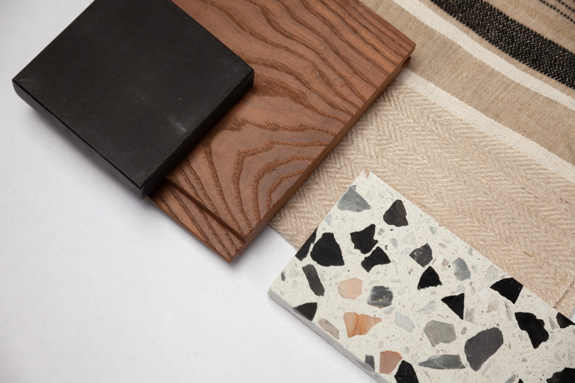 Black stone, timber, linen weaves and terrazzo arranged as a palette